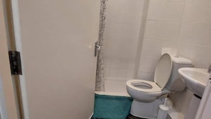 Un baño pequeño con inodoro, lavamanos y ducha.