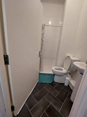 Um banheiro pequeno com vaso sanitário, pia e chuveiro.