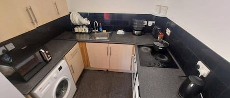 A compact kitchen with a washing machine, a sink, and a stove.