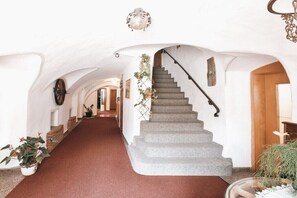 Ein Flur mit Treppe, weißen Wänden und Blumentöpfen.