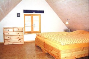 Ein Schlafzimmer mit einem hölzernen Bett, einer Kommode, einem Fenster mit Aussicht und einer Deckenleuchte.