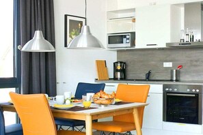 A modern kitchen with a dining table, chairs, and a breakfast setup. - Apartment in Plau am See with swimming pool (Plau am See)