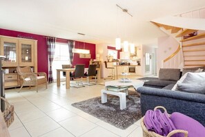 Ein modernes Wohnzimmer mit einer Couch, einem Esstisch und einer Küchenzeile.