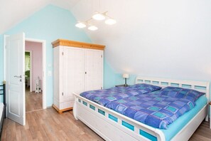 Ein Schlafzimmer mit einem Bett, einem Kleiderschrank, einer Tür zu einem anderen Raum und einer Deckenleuchte.