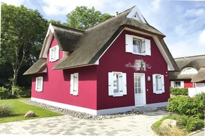 Ein rotes Gebäude mit weißen Fensterläden, einer Tür und einem Schornstein.