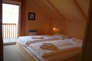 A room with two beds, a wooden ceiling, a picture on the wall, and a window with curtains. - Cabin with 1 bedroom (Stadl an der Mur)