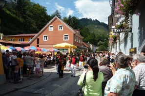 A street with people, a building with a sign, and a mountain in the background. - Cabin with 1 bedroom (Stadl an der Mur)