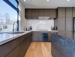 A modern kitchen with a built-in oven, a coffee maker, and a sink. - Bisei (Kutchan)