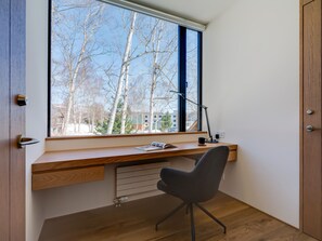 A modern office space with a large window, a desk, a chair, and a radiator. - Bisei (Kutchan)