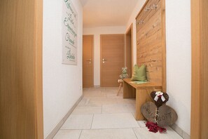 Ein Korridor mit Holztüren, einer Bank mit Kissen und einem an der Wand befestigten Schild.