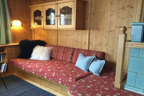 Ein Holzblockhaus-Interieur mit einer Couch, einem Schrank mit Glastüren und einer Lampe.