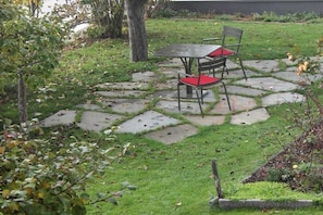 Ein Garten mit einem Kiesweg, einem Tisch und zwei Stühlen.