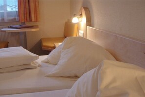 A hotel room with a bed, a chair, a desk, and a lamp. - Edelweiss Guesthouse in the Ötztal Valley (Sautens)