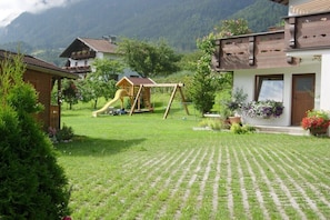 A residential area with a grassy yard, a wooden play structure, and houses with balconies. - Edelweiss Guesthouse in the Ötztal Valley (Sautens)