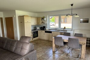 A compact kitchen with a dining area, a sofa, and a window providing natural light. - Müritzblick No. 11 Ground Floor (Röbel \/ Müritz)
