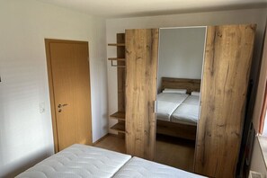A room with a bed, a wooden wardrobe, and a door. - Müritzblick No. 11 Ground Floor (Röbel \/ Müritz)