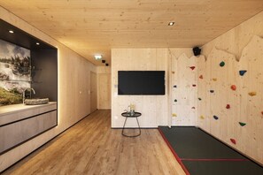 Ein Kletterzentrum mit Holzwänden, einem Fernseher und einem kleinen Tisch.