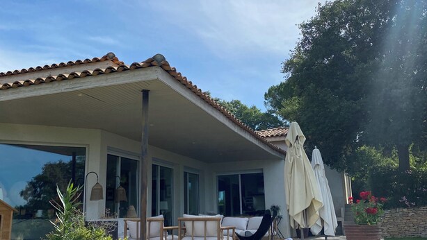 A covered patio with outdoor furniture, a large potted plant, and a stone wall. - Beautiful contemporary architect-designed home with a pool and garden set amid the garrigue (Nîmes)