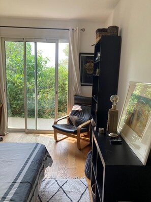 A bedroom with a bed, a chair, a desk, and a large window with a view of greenery. - Beautiful contemporary architect-designed home with a pool and garden set amid the garrigue (Nîmes)