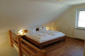Ein Schlafzimmer mit einem hölzernen Bett, weißer Bettwäsche, zwei Nachttischlampen und einem Fenster.