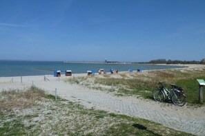 Ein Strand mit einem Fahrrad, einem Sandweg und einem entfernten Steg.