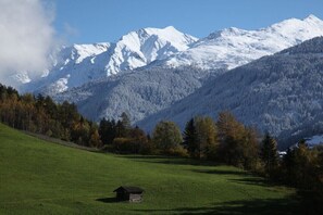 Eine Berglandschaft mit einer kleinen Holzhütte auf einem grasbewachsen Hügel.
