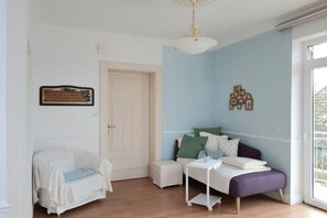A room with a white sofa, a small white table, and a purple bench. - V "Engelwiese" - House of Avalon (Grube)