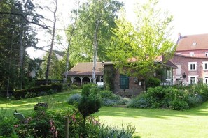A garden with a gazebo, a brick building with a red roof, and a signboard. - V "Engelwiese" - House of Avalon (Grube)