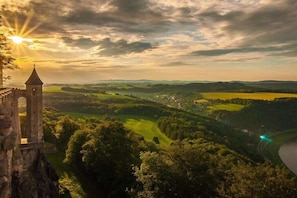 Ein historischer Turm mit Blick auf ein Tal und einen Fluss, umgeben von üppigem Grün.
