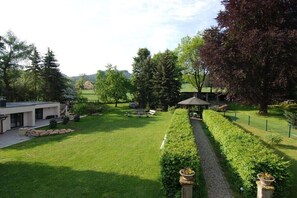 Ein gepflegter Garten mit einem Pavillon, einem Weg und einem modernen Gebäude.
