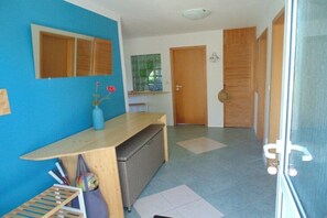 Ein Zimmer mit blauer Wand, einem Holztisch, einem Korbwäscher, einem kleinen Fenster und einer Tür.