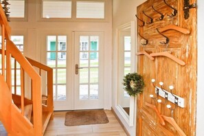 A wooden staircase leading to a door with a coat rack and a wreath. - Holiday home with 4 bedrooms (Ostseebad Rerik)