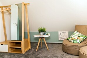 A room with a wooden wardrobe, a small round table with a plant, a bean bag chair, and a wall with a word cloud poster. - Holiday home with 4 bedrooms (Ostseebad Rerik)