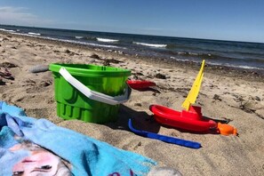 A beach with a green bucket, a red toy boat, and a blue shovel. - Holiday home with 4 bedrooms (Ostseebad Rerik)