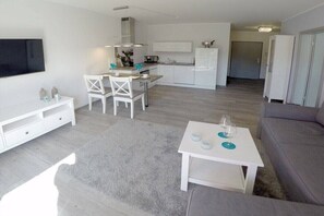 Ein modernes Wohnzimmer mit einem grauen Sofa, einem weißen Couchtisch und einem an der Wand befestigten Fernseher.