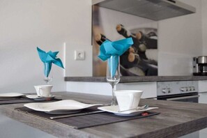 Ein Esstisch mit Tellern, Besteck und einem Glas mit blauem Servietttuch.