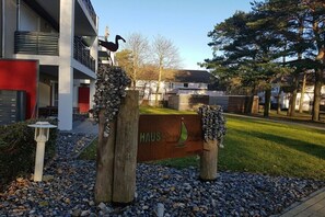 Ein Gebäudeeingang mit einem Schild, einem hölzernen Pfosten mit einer Vogel-Skulptur und einer Steinmauer.