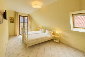 A bedroom with a bed, bedside tables, a window, a door, and a ceiling light. - Beach House Sea Star (Glowe)