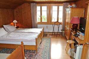 A wooden room with a bed, a small table, a TV, and a cabinet.