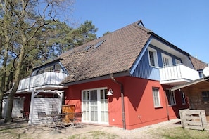 Ein zweistöckiges Haus mit roter Fassade, einem Balkon und einer Garage.