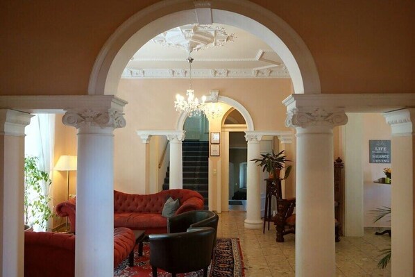 Eine prächtige Lobby mit einem roten Sofa, einem schwarzen Sessel und einer Chandelier.