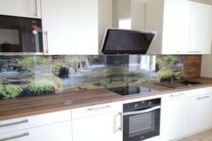 A kitchen with a built-in stove, oven, and a large window above the sink.