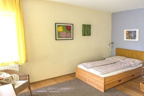 A bedroom with a bed, a chair, a table, and two wall-mounted pictures. - Holiday apartment in Pirna with swimming pool (Pirna)