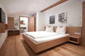 A modern bedroom with a wooden bed, built-in bench, and artwork on the walls. - 100 m² Guesthouse Sonne (Bichlbach)