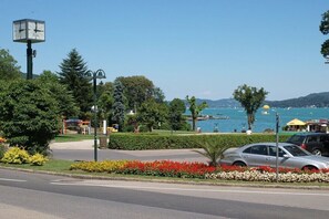 Ein Park mit einer Uhr, einer Straße und einem Gewässer im Hintergrund.