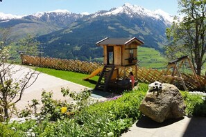 A wooden play structure with a slide, set against a backdrop of snow-capped mountains. - Holiday apartment with 1 bedroom (Piesendorf)