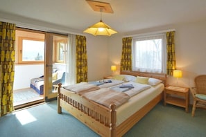 A bedroom with a large bed, two bedside lamps, a wooden nightstand, and a chair. - Cottage/Chalet Mag. Scholz (Seeboden am Millstättersee)