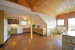 A spacious kitchen with wooden beams, a dining area with chairs, and a view through the windows. - Cottage/Chalet Mag. Scholz (Seeboden am Millstättersee)