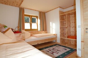 Ein Zimmer mit einem Bett, einem Fenster, einem Holzschrank und einem kleinen Tisch.