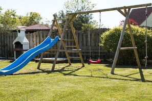 Ein Spielplatz im Garten mit Rutsche, Schaukel und Kletterleiter.